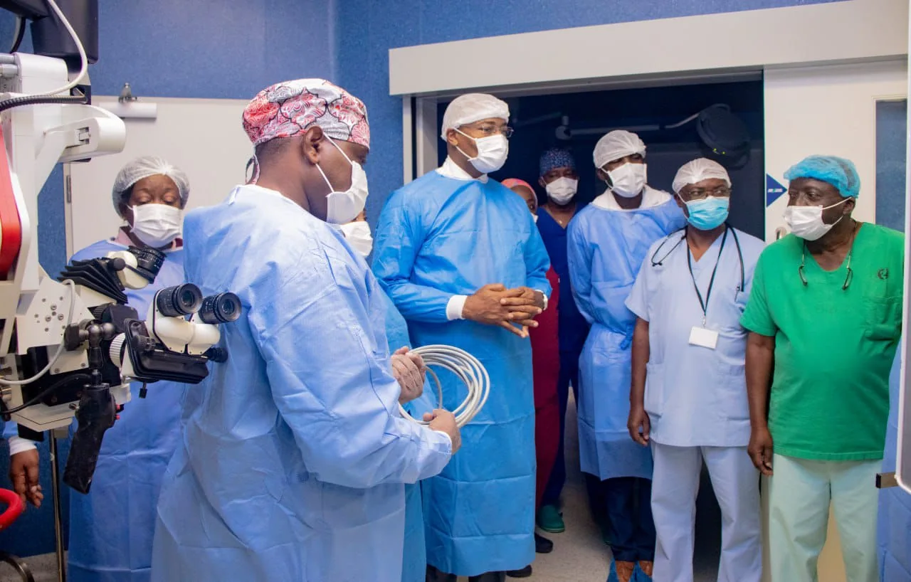 Medical team in surgical attire in front of an operating microscope, in the operating theatre